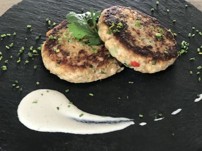 2 hamburguesas con pescado sobre pizarra con salsa blanca